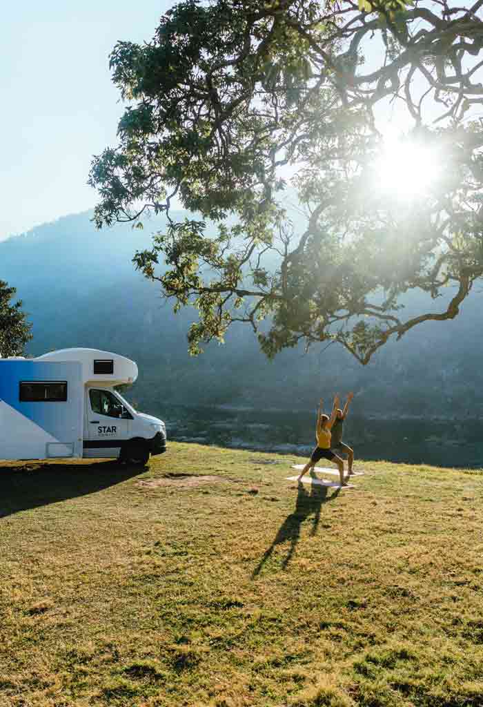 Couple doing yoga by riverbank