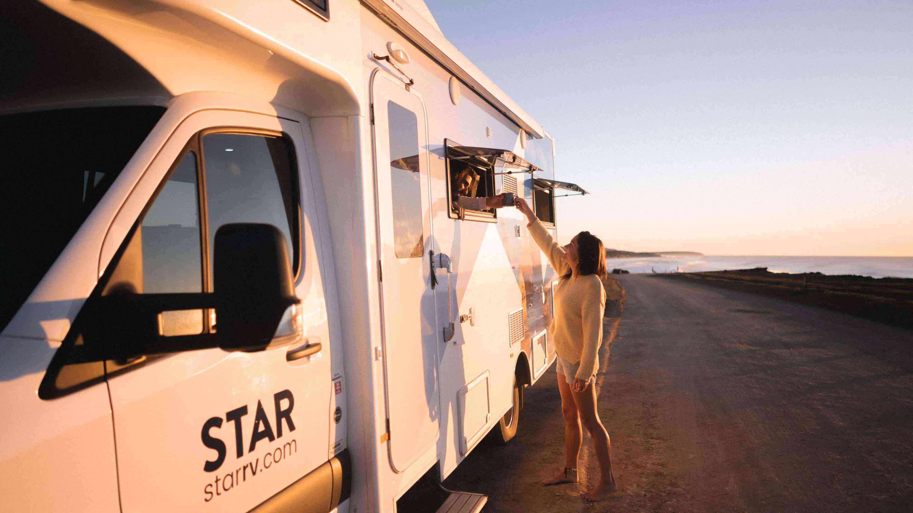 Woman taking mug of coffee from motorhome open window